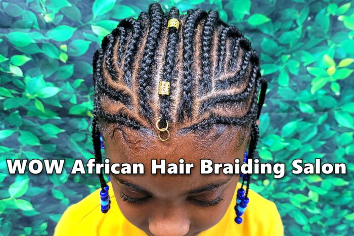 Child with traditional Fulani braids decorated with gold clips and beads at kids hair salon.